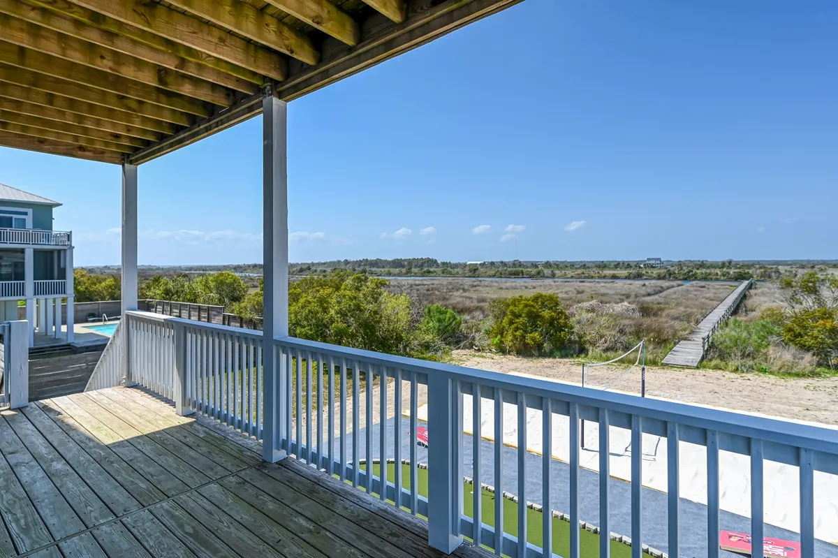 This view from a spacious deck captures an expansive landscape with a pathway leading into the distance. The open skies and sunlit surroundings evoke a sense of freedom and possibility, inviting guests to explore the natural beauty that stretches beyond the property.