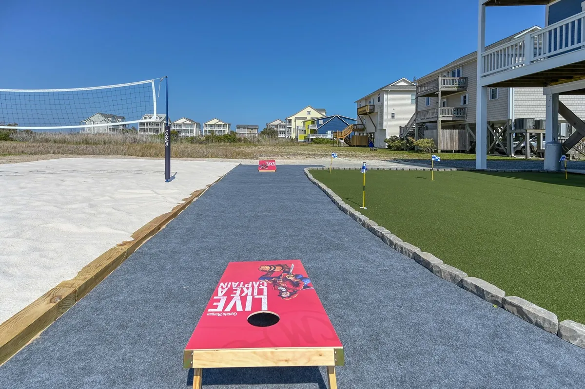 A vibrant exterior shot highlighting a backyard setup complete with a volleyball net, cornhole boards, and a putting green, all arranged for group activities. The area is spacious and clearly designed for family games and friendly competitions.