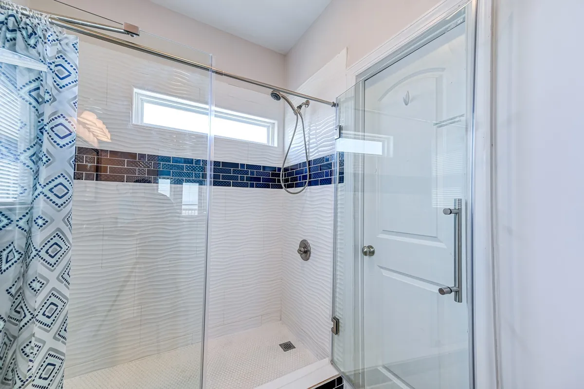 A spa-like bathroom with a glass shower enclosure accented by striking blue tiles and modern fixtures. The space is bright, clean, and designed for rejuvenation.