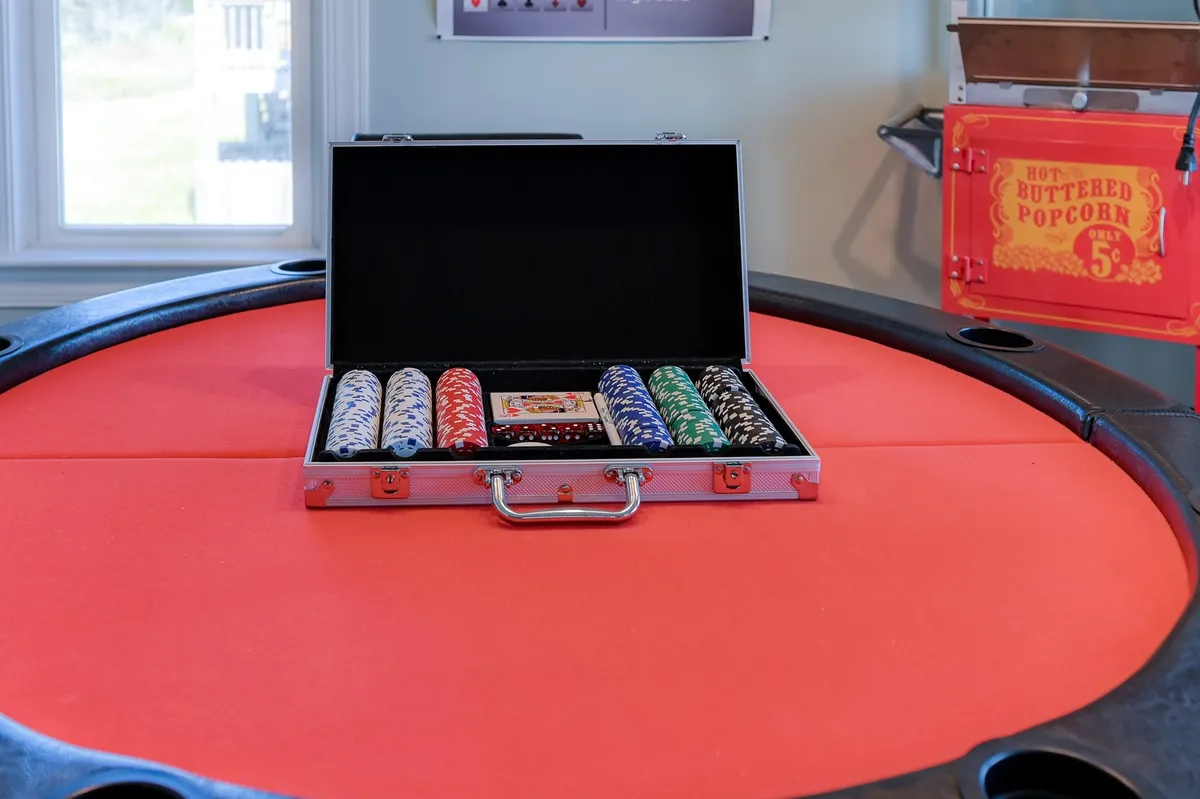 A lively game room featuring a poker table with neatly stacked poker chips and a classic popcorn machine in the background. The setup is inviting for adult gatherings, exuding the energy of a true 'man cave' perfect for game nights and friendly competition.