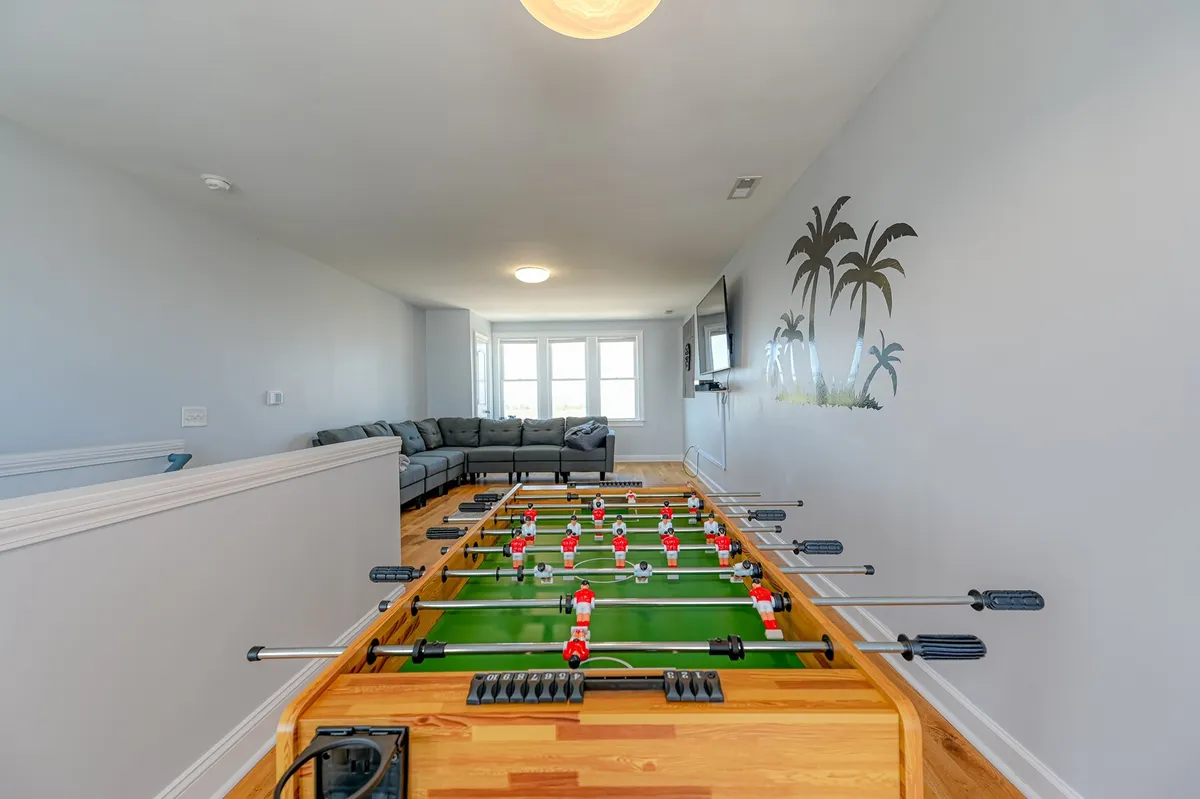 A relaxed recreation area with a foosball table, comfortable sofa seating, and large windows that flood the room with daylight. The setting encourages friendly matches and casual socializing in a laid-back environment.